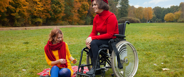 Niepełnosprawna kobieta na wózku inwalidzkim z towarzyszącą osobą